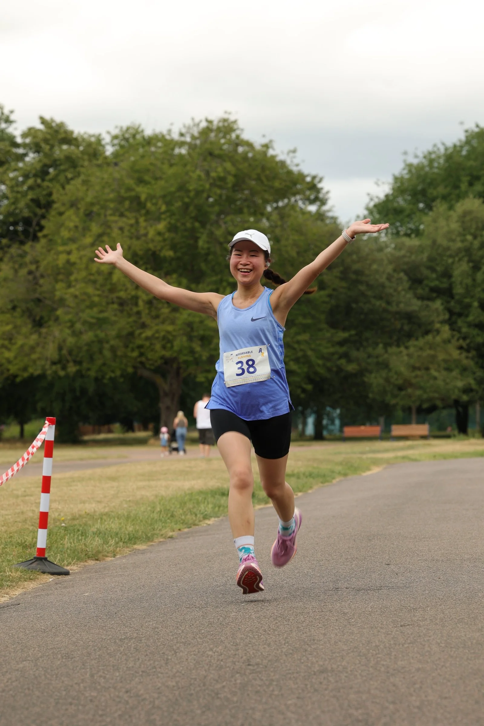 A smiling 5K finisher with her arms raised